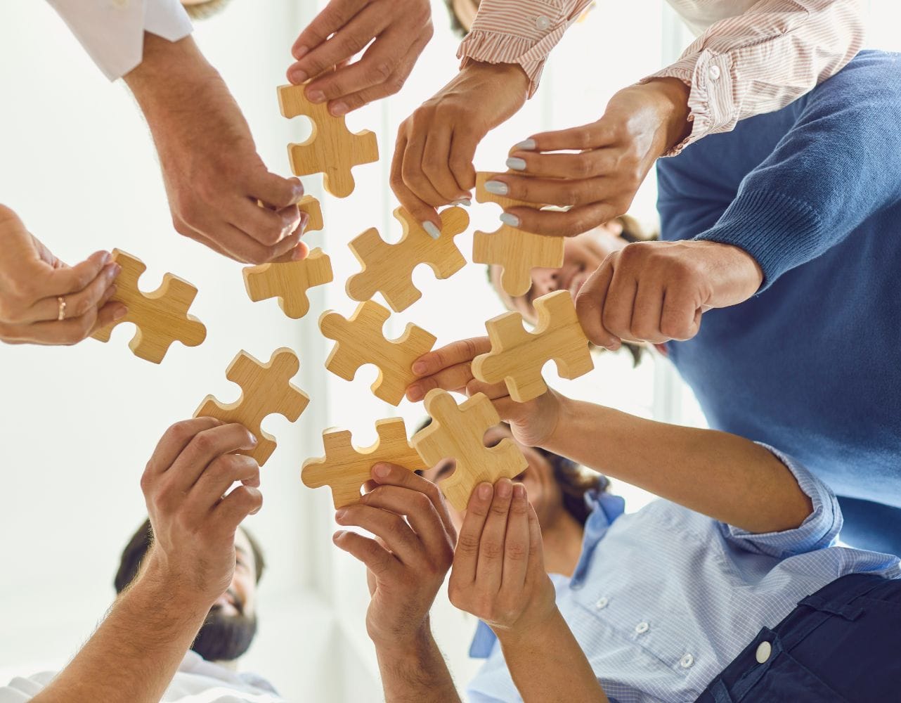 Team members collaborate on a wooden puzzle to develop strategic communication and rapport