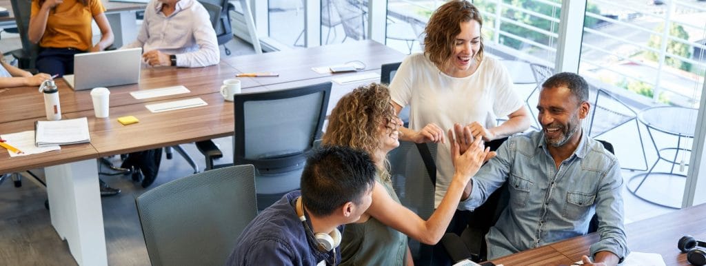 a happy team working together to promote workplace wellbeing